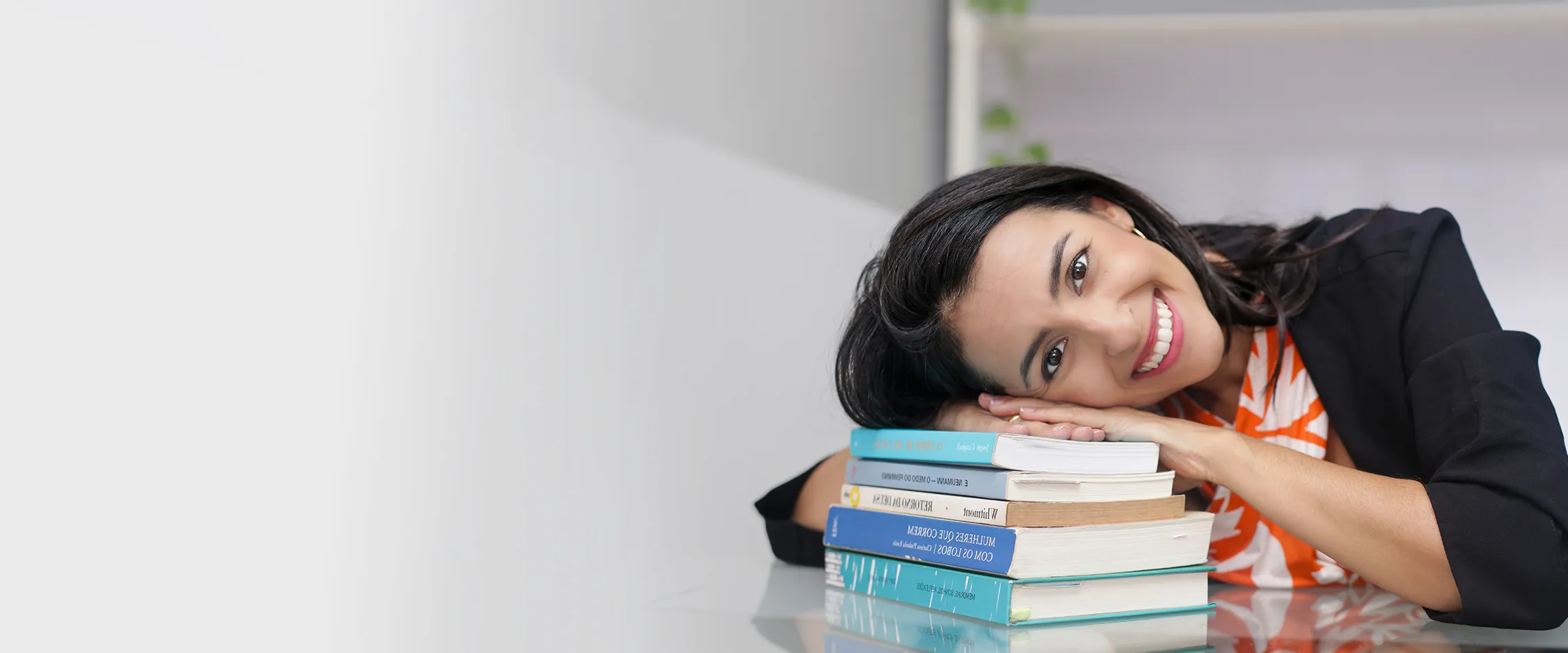 Natália Pozzatto, psicóloga, apoiada sobre uma pilha de livros